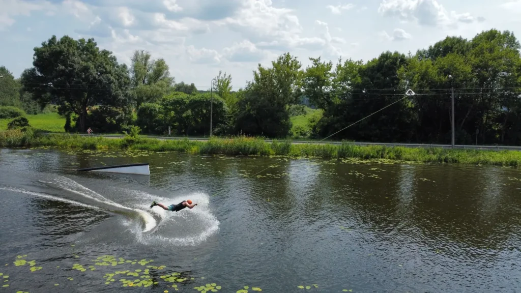Praticante deslizando sobre a água em uma prancha durante sessão do esporte wakeboard em cable park