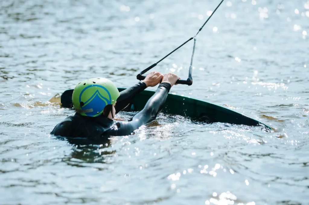 Praticante de wakeboard deslizando sobre a água com prancha e cabo em dia ensolarado, equipamentos de wakeboard em uso