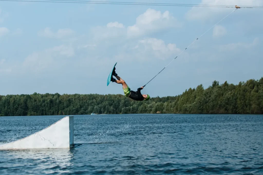 Praticante em pé sobre prancha executando manobra no cable park, ilustrando o que é o esporte wakeboard