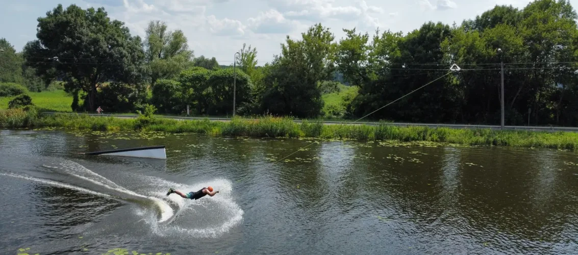 Praticante deslizando sobre a água em uma prancha durante sessão do esporte wakeboard em cable park