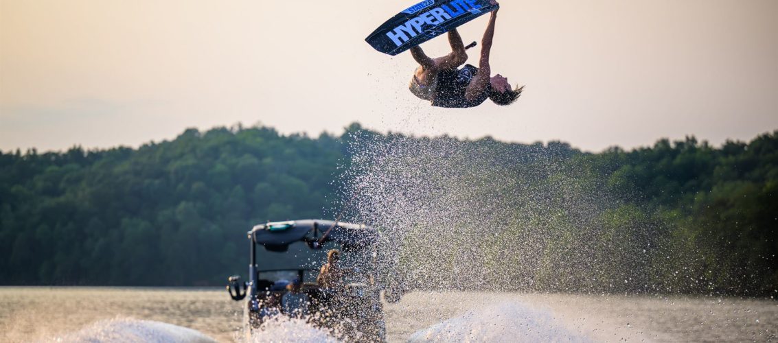 Rider executando manobra aérea no wakeboard atrás do barco