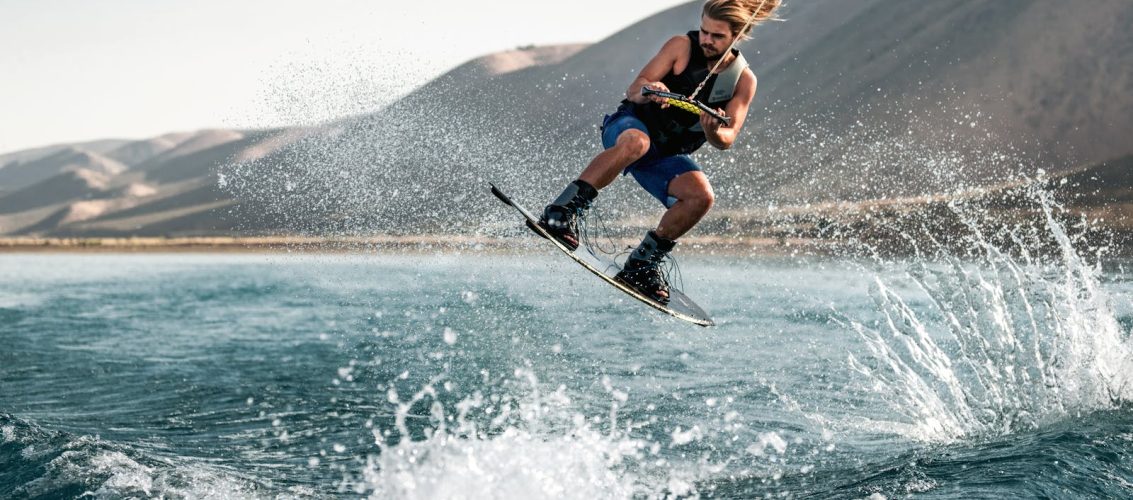 Wakeboarder em manobra aerea durante pratica de wakeboarding