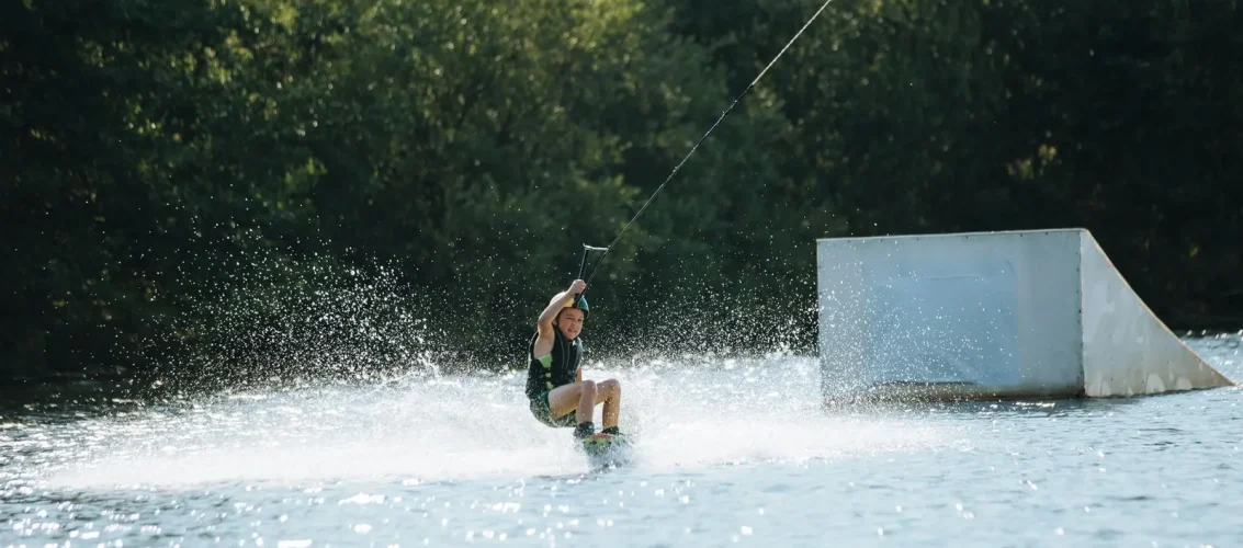 Praticante de wakeboard equipado com colete de impacto e capacete em wake park, pronto para sessão segura